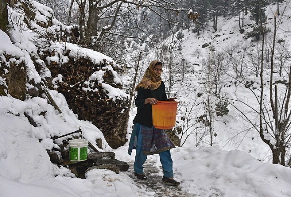 Girl walks with a bucket of water on the snow-covered trail in Kashmir Valley. (Photo: PTI ) Representational Picture