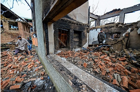 Villagers walk past the debris after a gun battle between security forces and terrorists at Tral in Pulwama district of South Kashmir on March 11, 2019. The terror mastermind of February 14 Pulwama terrorist attack was killed in this encounter. (Photo: PTI)