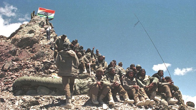 Indian soldiers pose with the Tricolour after capturing a peak from Pakistani intruders during the Kargil War, 1999.