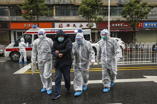 Hospital assistants in protective suit taking away a COVID-19 patient (in black dress) in China’s Hubei Province. (File Photo: AP)