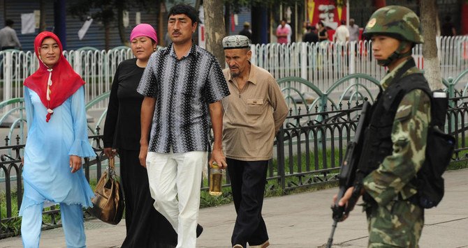 A Chinese policeman on guard as an Uighur Muslim family passes by in Urumqi, Xinjiang region. (File photo: AFP)