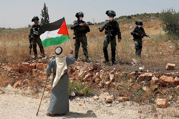 A Palestinian stands in protest against Israeli soldiers. (File Photo: Reuters)